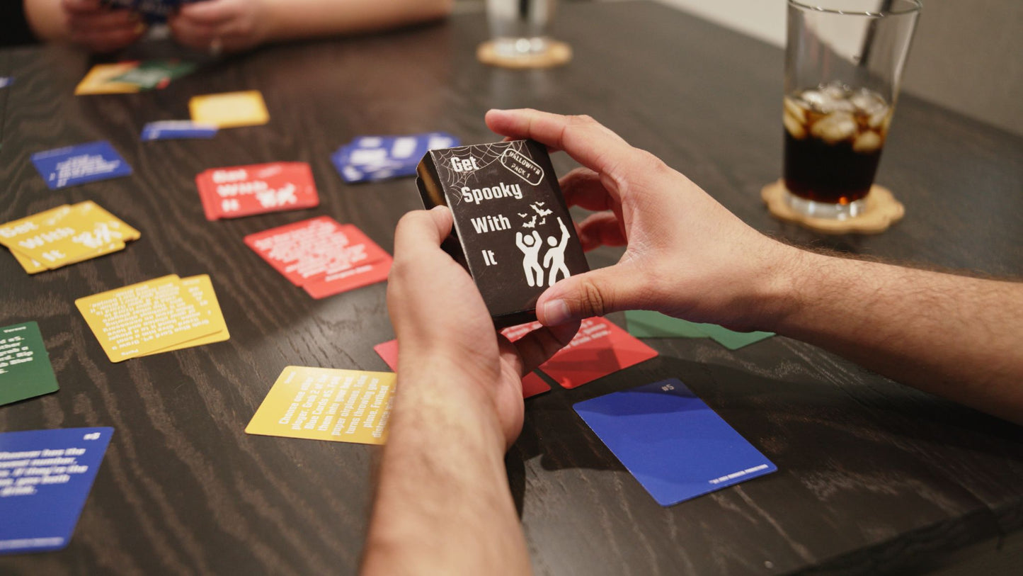 someone holding Get Spooky With It a Halloween expansion for Get With It