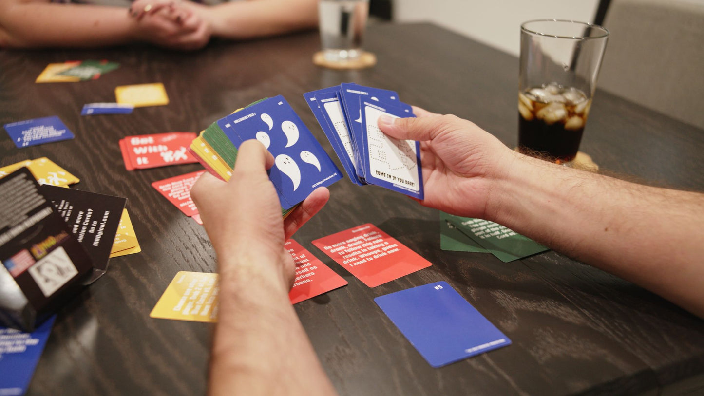 someone holding cards for Get Spooky With It a Halloween expansion for Get With It